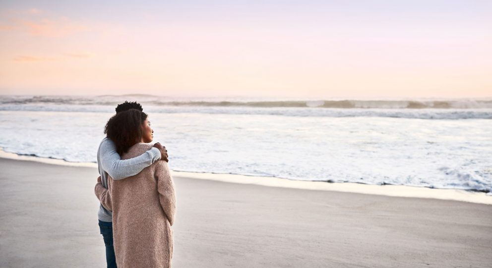 Image of couple standing and hugging at the beach.