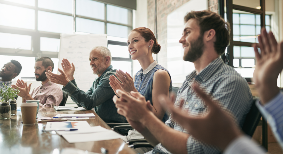 image of group of people sitting at tables applauding and providing positive feedback