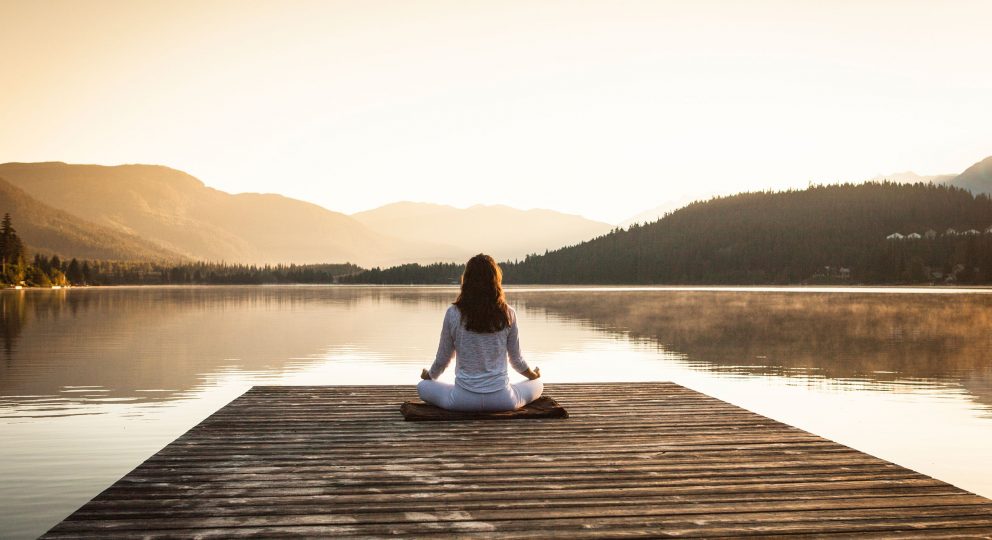 Building Your Marriage on the Four Foundation of Mindfulness. Image of woman peacefully sitting at the end of a dock with a calm body of water in front of her.